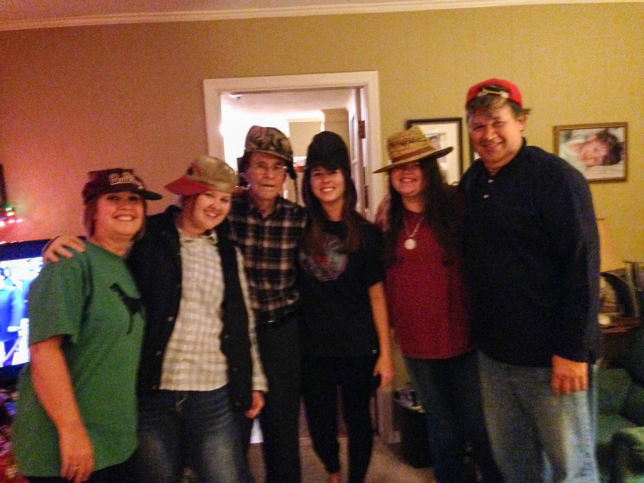 Six people posing for a picture with hats on their head.